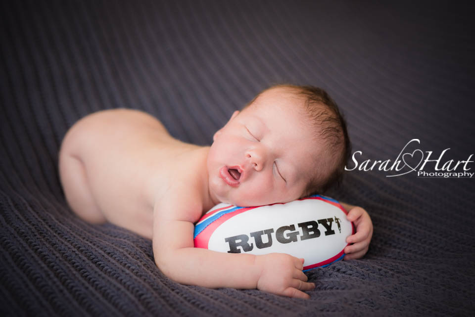 newborn baby with rugby ball, sleepy posed newborn photos, Kent photographer