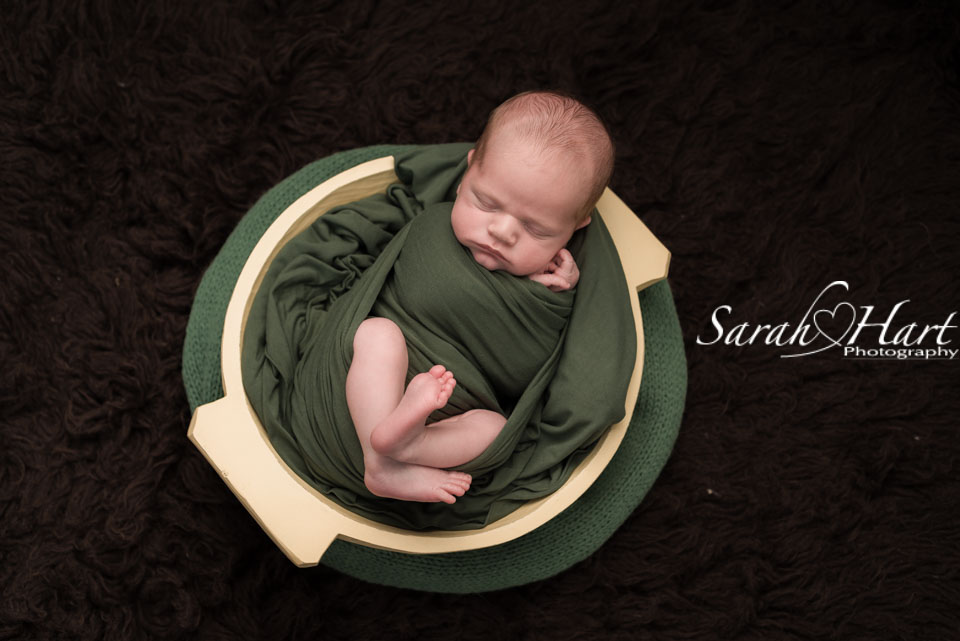 newborn baby in bowl, using dark forest green tones