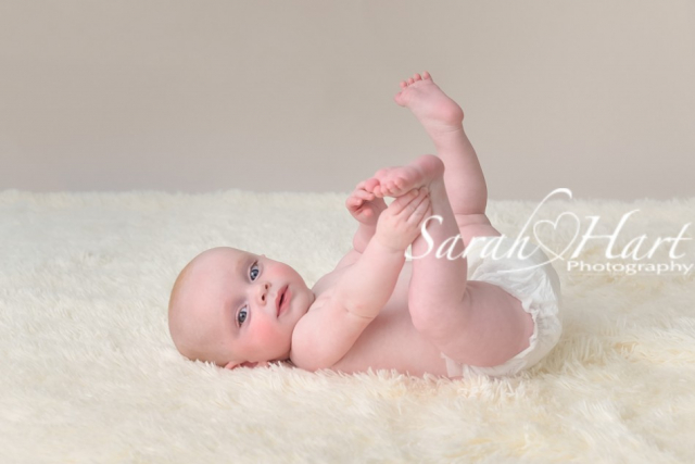 baby rolls, baby on back, holding feet, baby fingers and toes, family session, photography by Sarah Hart