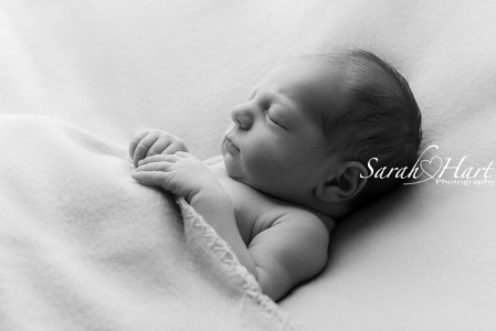 Sleepy newborn tucked up in blanket, black and white baby photos kent