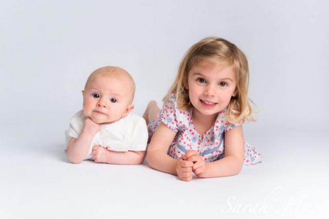 sisters, cute baby pose, white backdrop, baby 4 months old on tummy, kent baby pictures