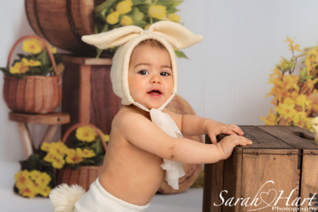 baby girl in bunny outfit stood at crate, mini session photography in kent