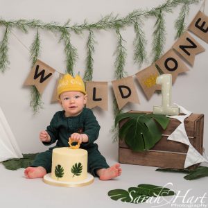 little boy celebrating first birthday at his cake smash photography session with wild one theme