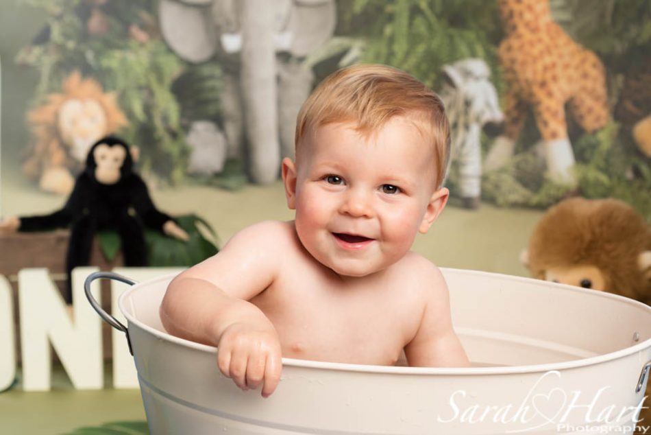 baby in a bath at his jungle theme cake smash
